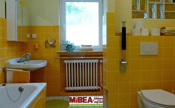 Das freundlicher, gelbe Badezimmer mit einer bodentiefen Dusche, rechts um die Ecke.