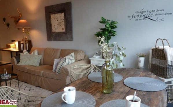 Esstisch mit Tassen, Blume  und Couch mit Bild und Pflanze