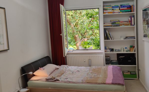 Bett und Fenster daneben ein Regal