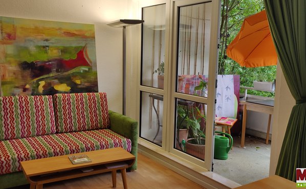 Links im Bild die Couch, darüber ein großes Bild, Lampe und Balkon rechts